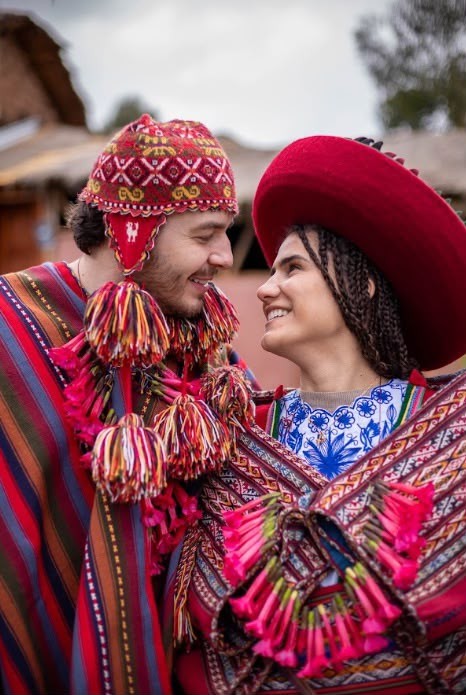 Bride and groom in traditional Andean dress smile at each other